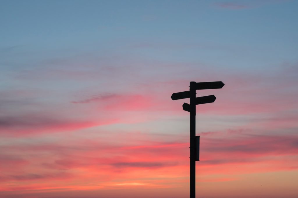 crossroads sign against a sunset, controlling