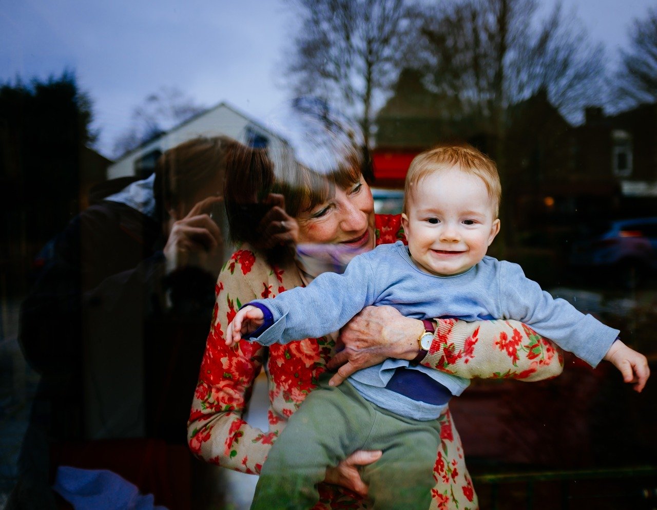 grandma with young grandson through window