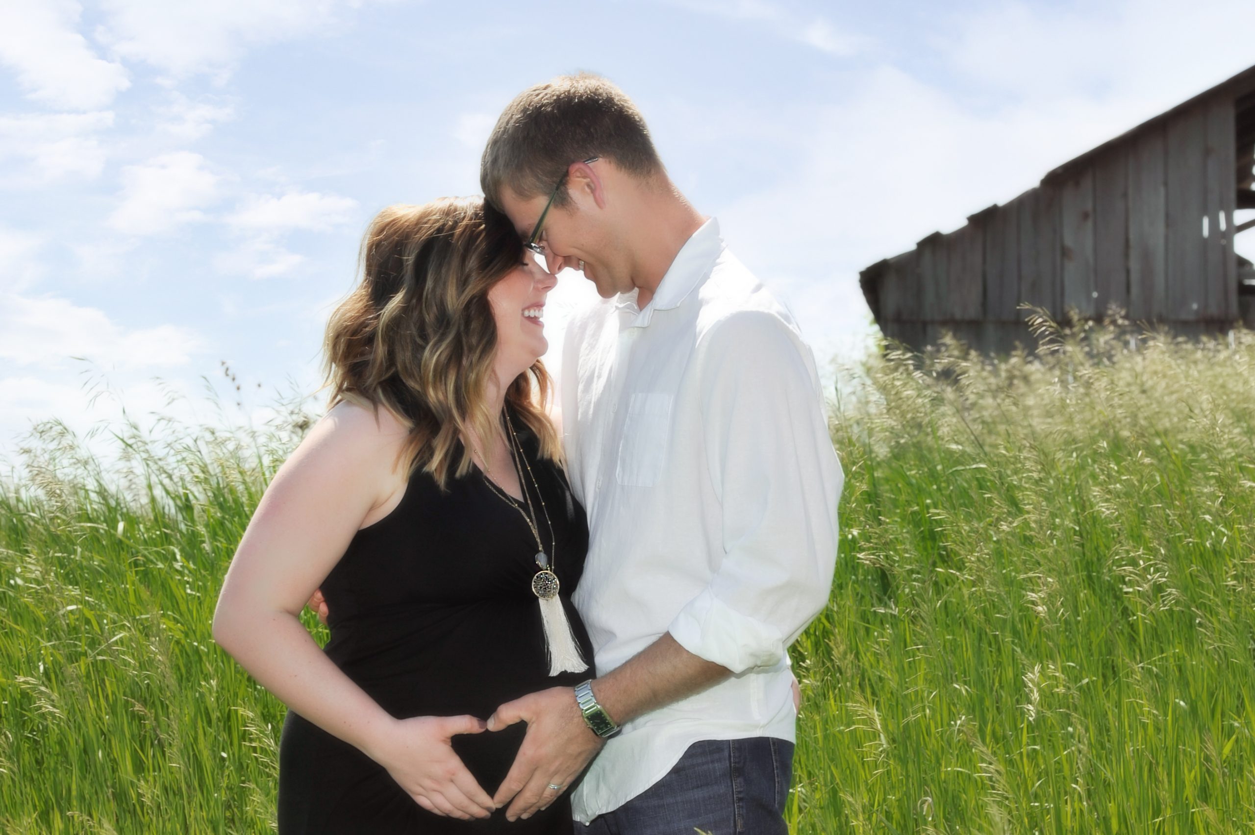 happy couple expecting a baby in a field on a sunny day